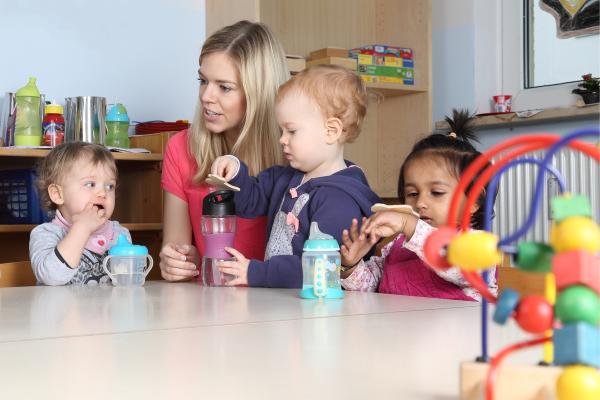 Frau mit langen blonden Haaren spielt mit Kindern
