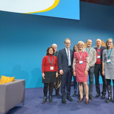 Eine Gruppe Menschen steht vor einer hellblauen Wand