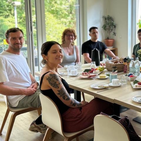 viele Menschen um einen gedeckten Tisch