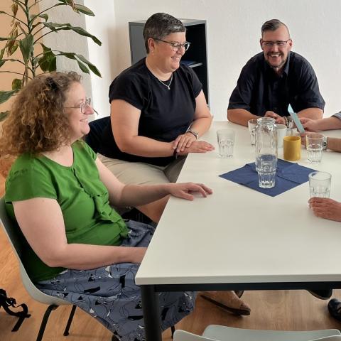 Menschen im Gespräch, an einem Tisch sitzend