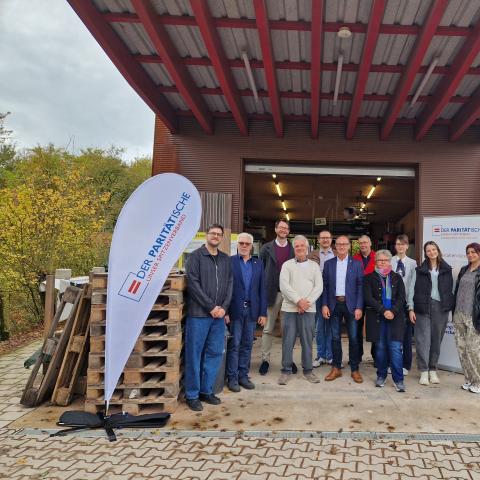 Herzlich willkommen mehrere Personen vor einer Werkstatt