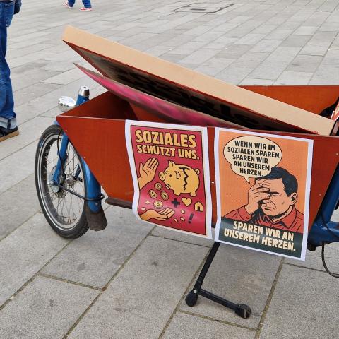 Demonstrationsschilder mit den Titeln Soziales Schützt uns und Wenn wir im Sozialen sparen, sparen wir an unserem Herzen