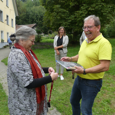 eine Dame und ein Herr &uuml;berreichen sich lachend ein Schl&uuml;sselband