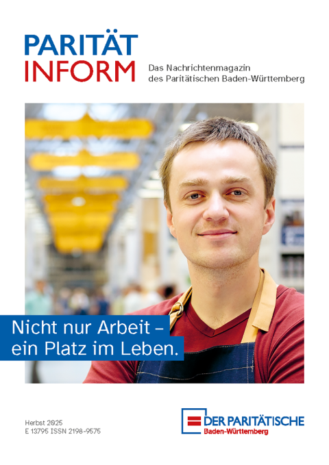 Junger Mann mit rotem T-Shirt und blauem Latz in einer Werkstatt