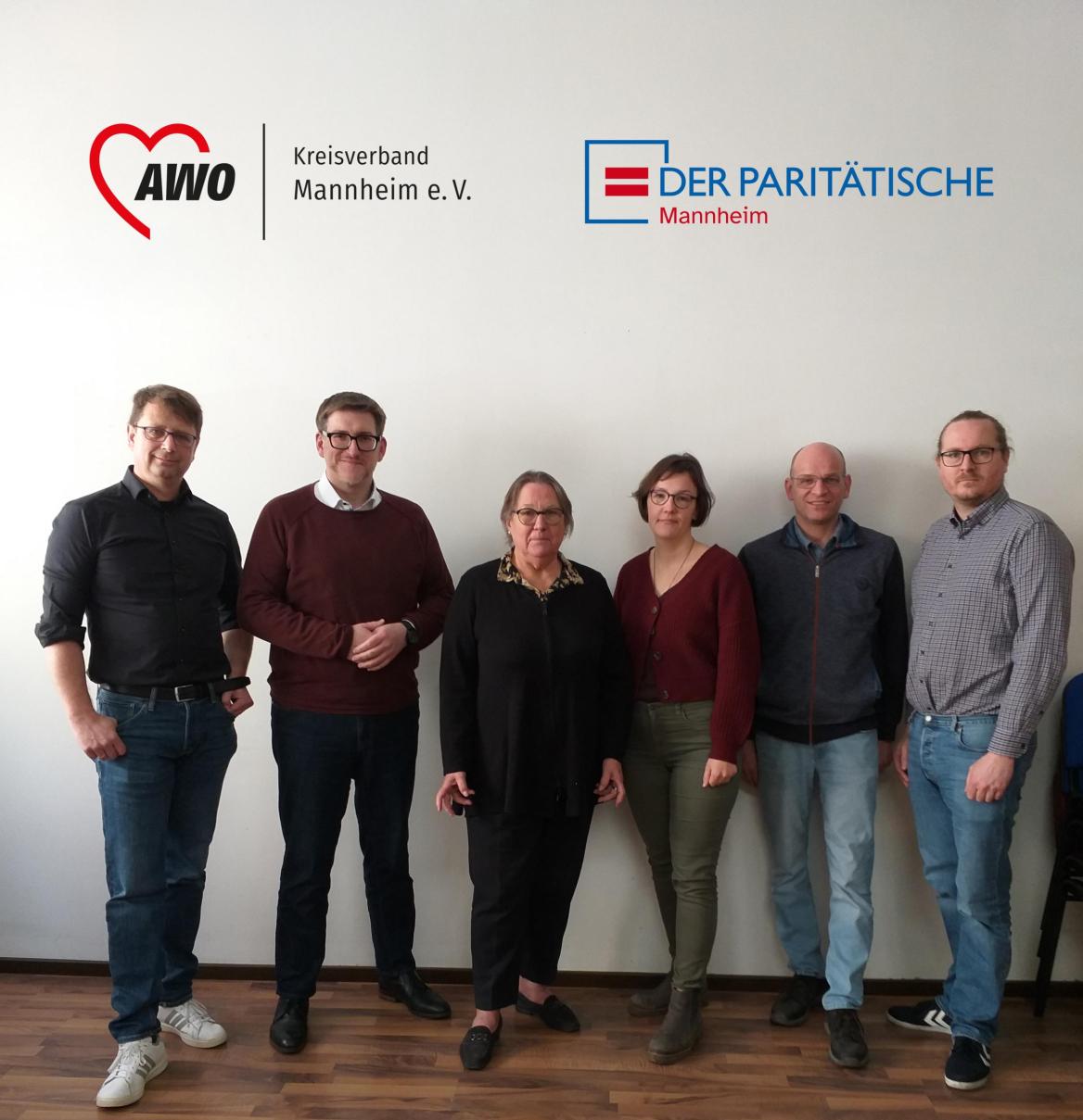 mehrere Menschenstehen  vor einer hellen Wand