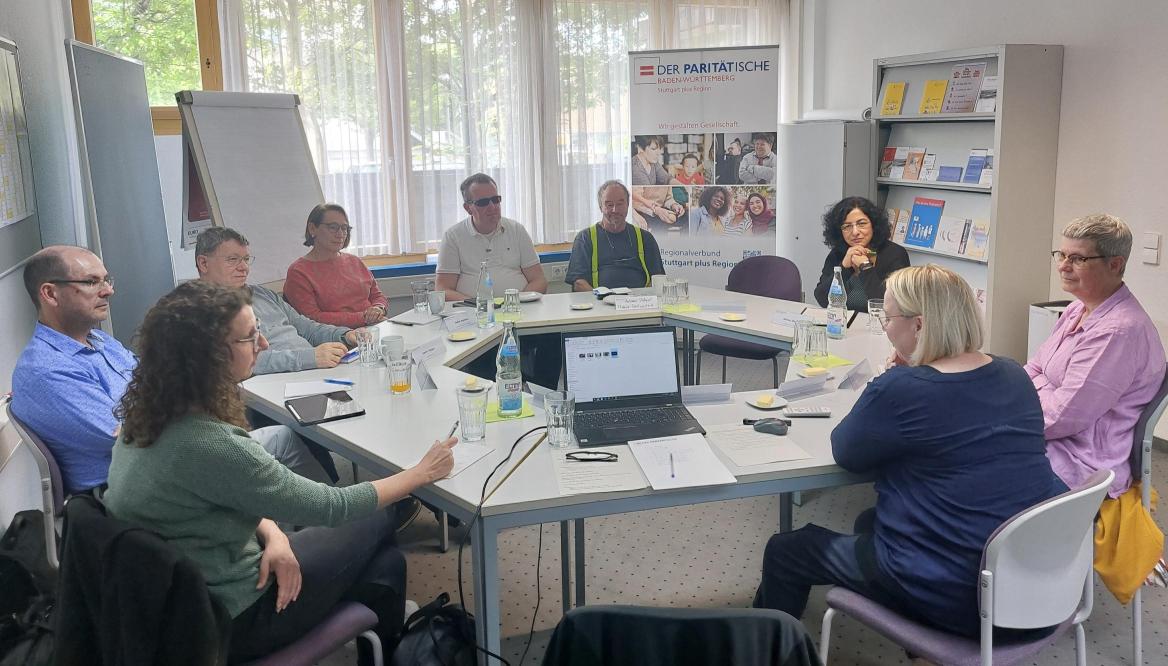 Personen sitzen im Tischkreis und diskutieren