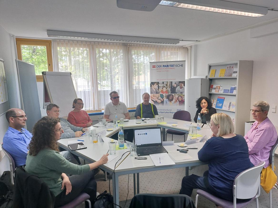 Personen sitzen im Tischkreis und diskutieren