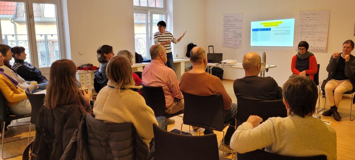 Tagungssituation; Teilnehmer*innen  schauen auf Bildschirm