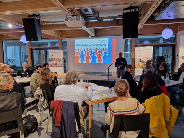 Wochenrückblick großer Raum mit einer Leinwand und vielen Menschen von hinten
