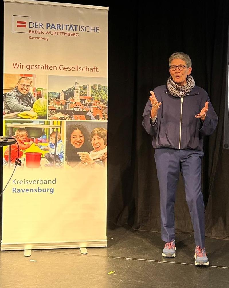 Eine Frau auf einer Bühne, im Hintergrund ein Roll-up