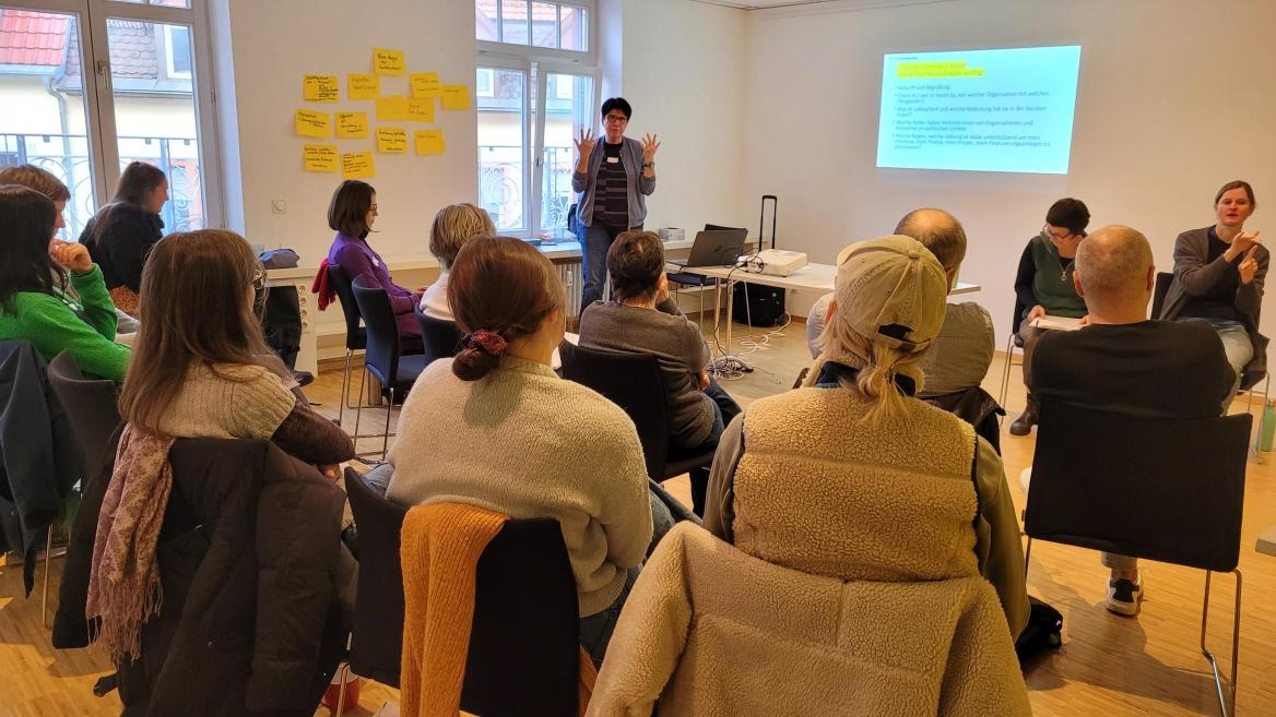 Die Referentin führt mit Hilfe der Präsentation in die Thematik ein, die Workshopteilnehmer hören aufmerksam zu