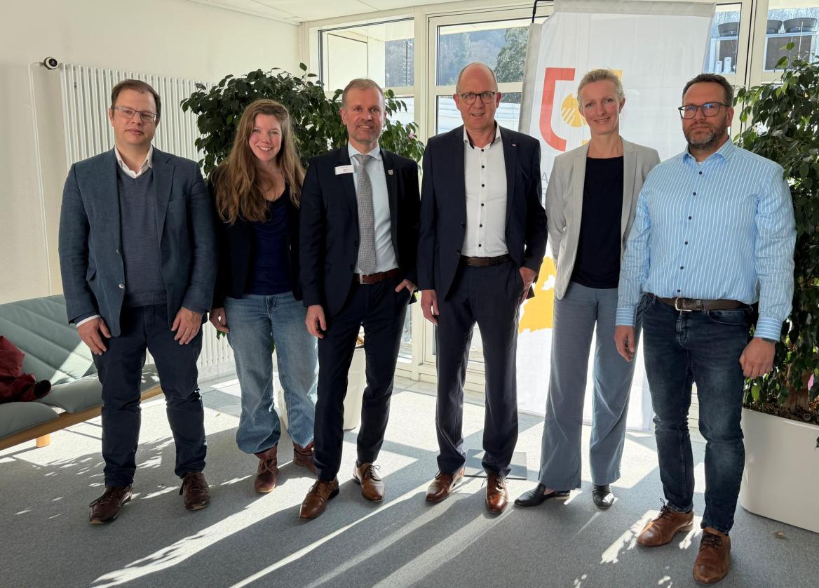 Sechs Menschen stehen nebeneinander vorm Logo des Landratsamts und lächeln in die Kamera