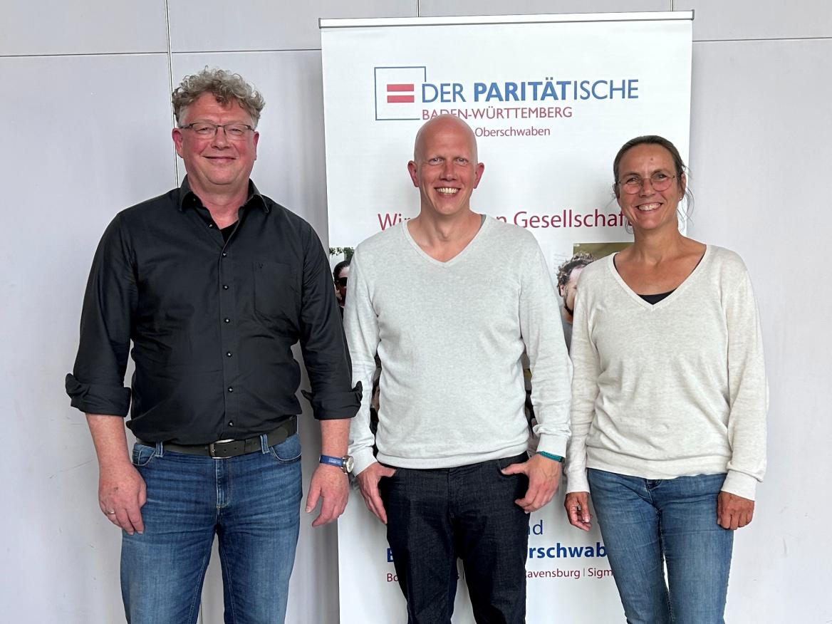 zwei Männer und eine Frau vor einem Plakat