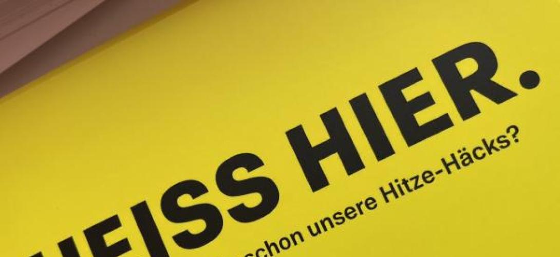 Heiss hier. Auf gelbem Grund. Postkarte
