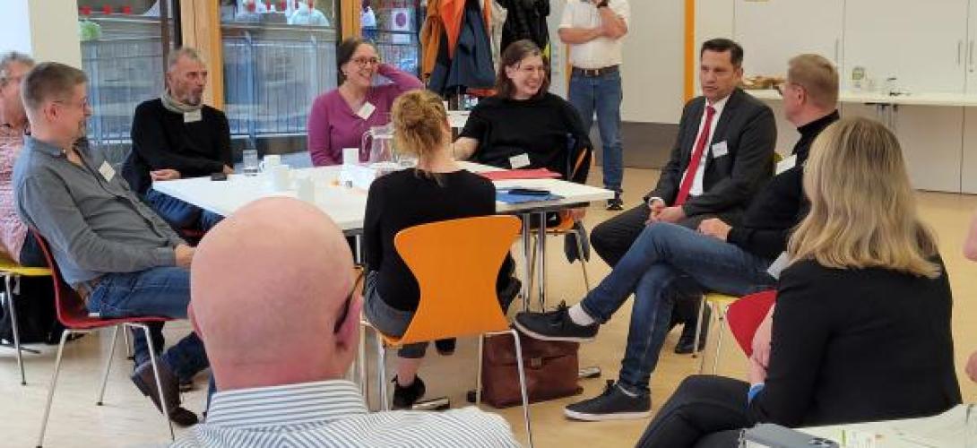 viele Menschen sitzen zusammen und diskutieren