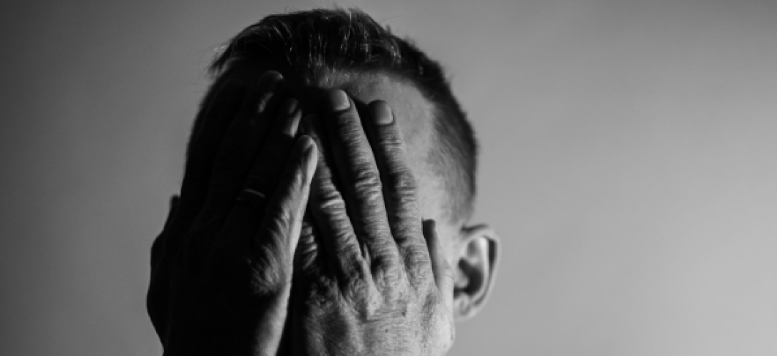 Mann hält sich beschämt die Hände vors Gesicht