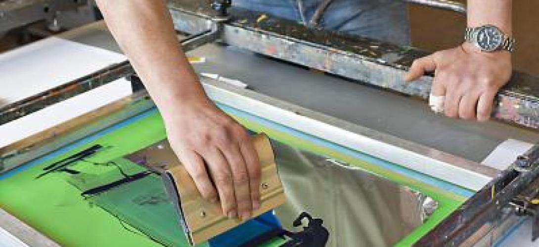 ein Mann streicht Farbe in einer grünen Wanne aus