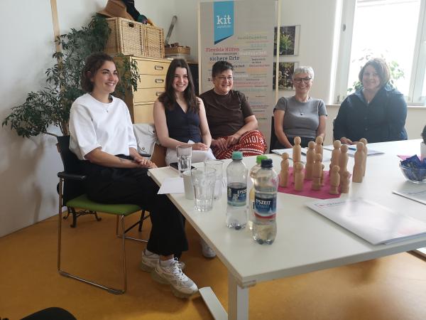 fünf Frauen sitzen an einem weißen Tisch