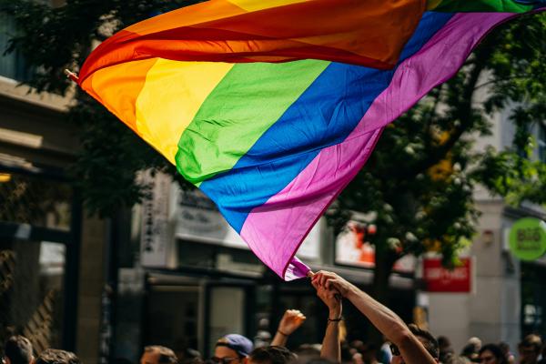 Mensch hält Fahne in Regenbogenfarben hoch