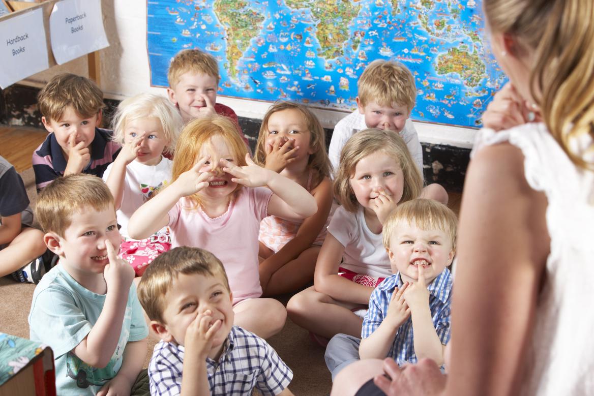 Erzieherin mit mehreren stitzenden kleineren Kindern 